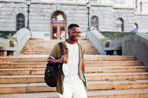 african-american-male-college-student-leaving-hall-and-smiling